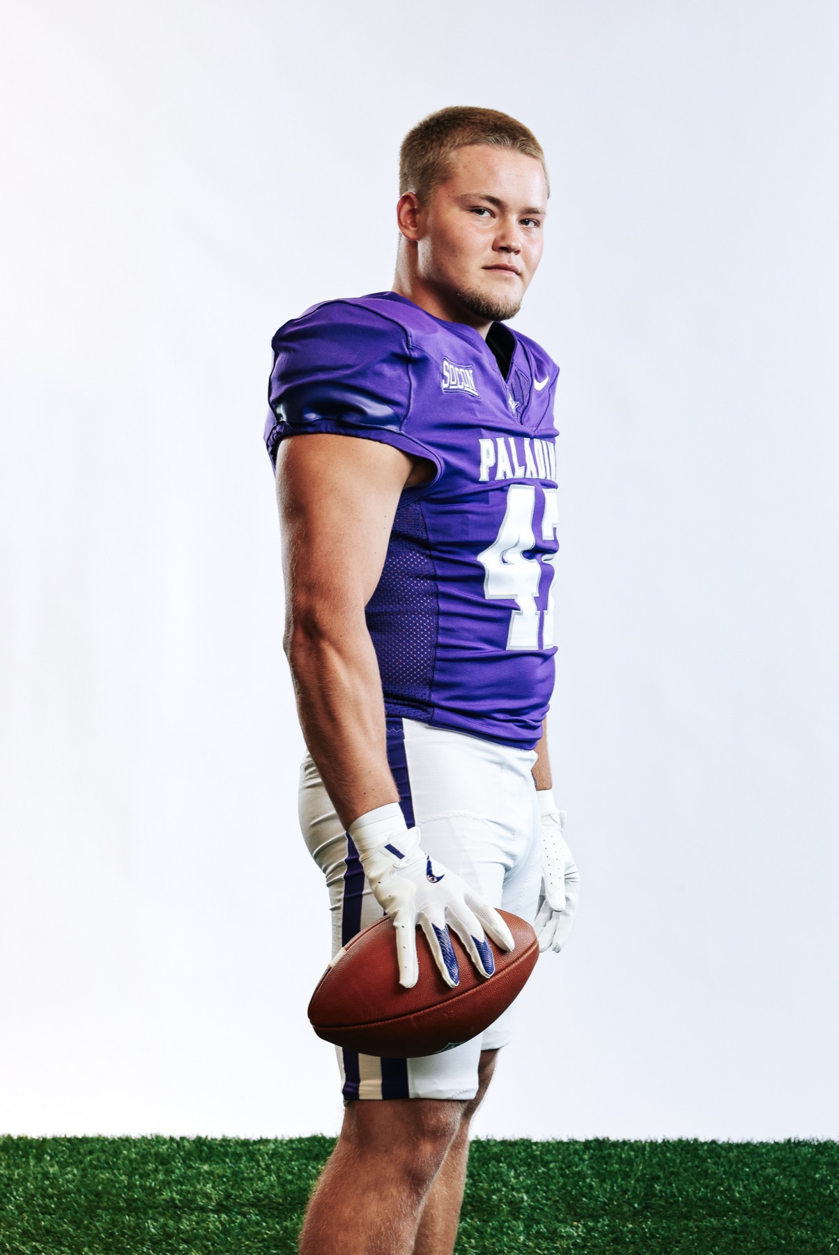 Jacob Hanson holding a football on Media Day in his purple Furman jersey